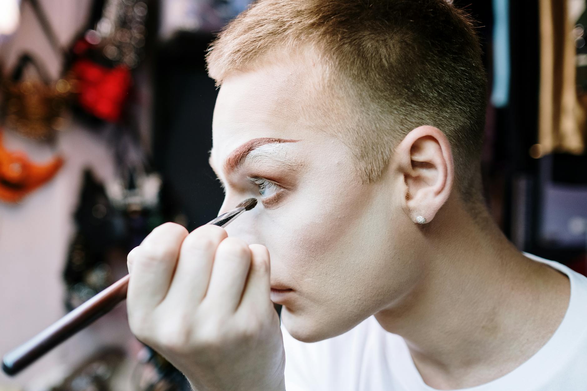 Makijaż sceniczny krok po kroku: jak stworzyć trwałą i efektowną stylizację na wielkie wyjście Drag queen wykonuje precyzyjny makijaż sceniczny w garderobie