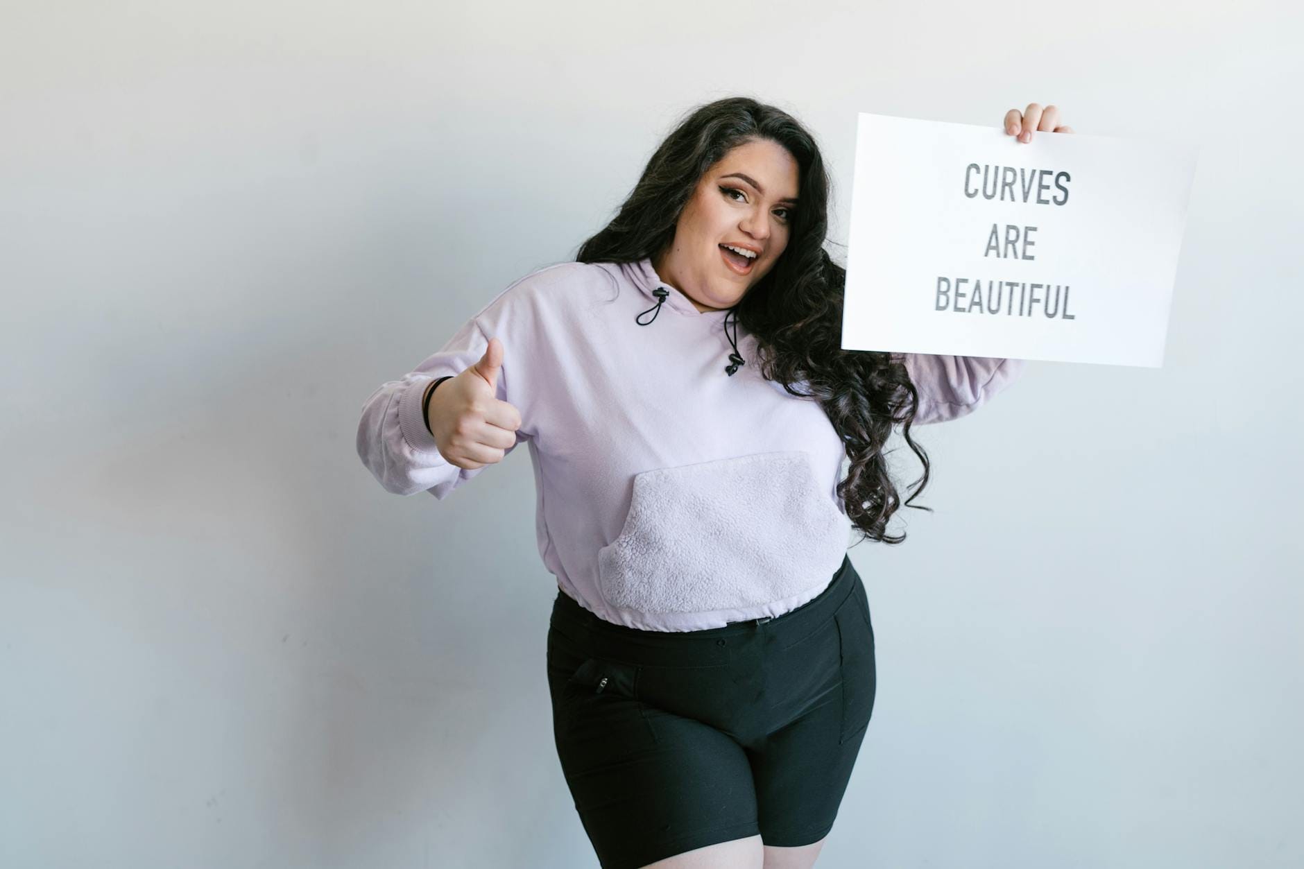 Uśmiechnięta kobieta plus size trzymająca plakat z napisem Curves Are Beautiful Uśmiechnięta kobieta plus size trzymająca plakat z napisem Curves Are Beautiful