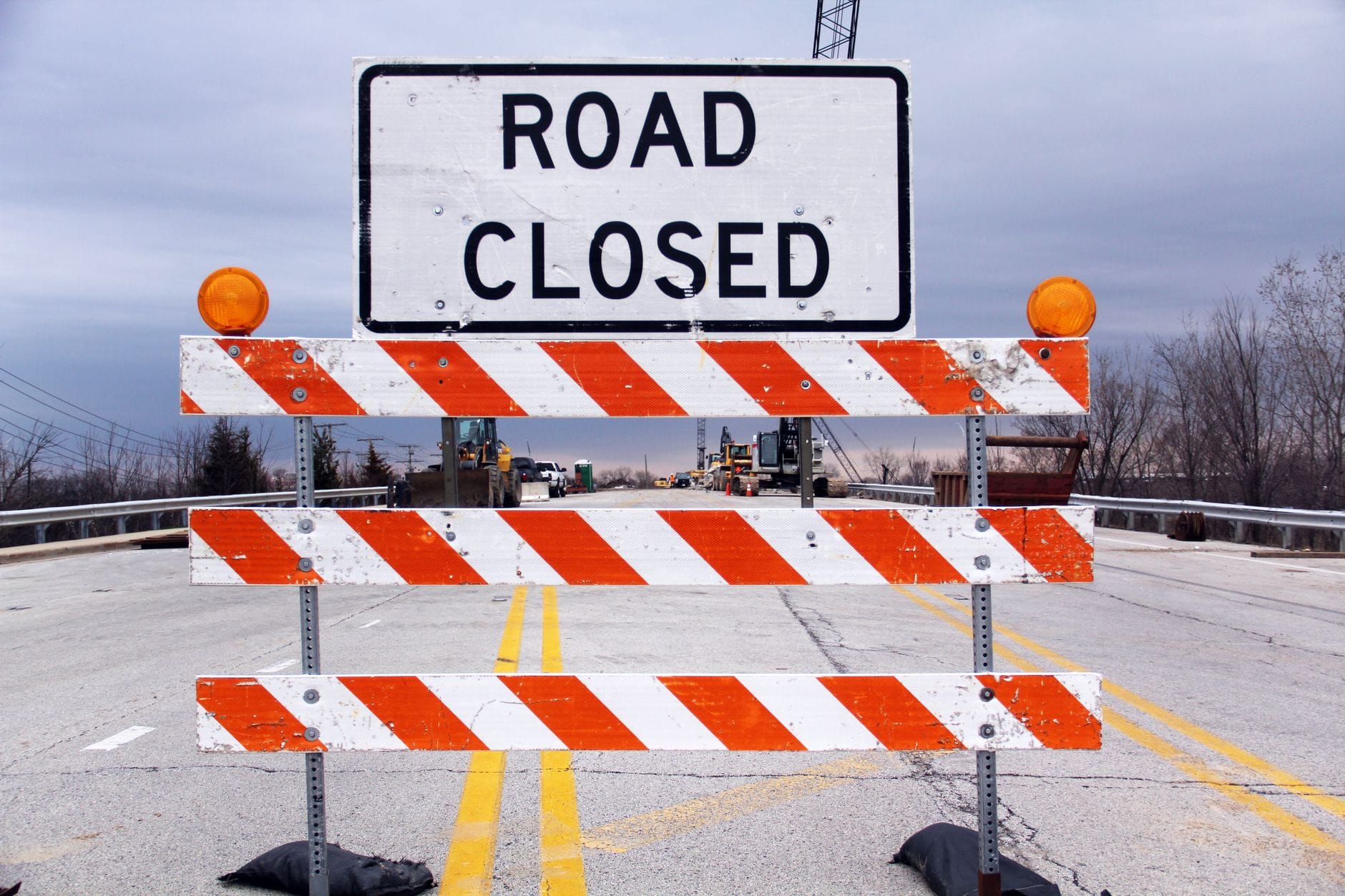Znak road closed i barierki blokujące ruch na podmiejskiej drodze